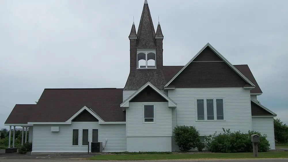 White clapboard church with a tall steeple, painted by the crew